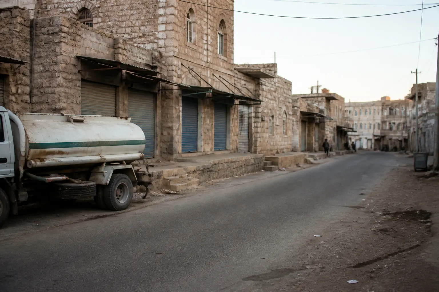 A quiet street with stone buildings and closed shopfronts in a southern Yemeni town