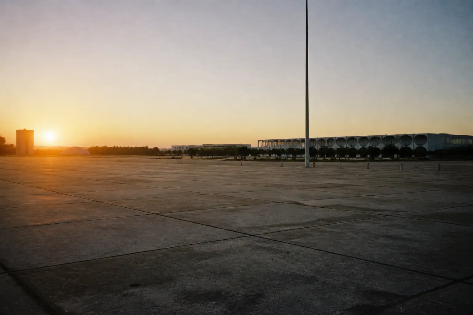 An empty modernist plaza in Brazil's purpose-built capital at dawn, government buildings in the distance.