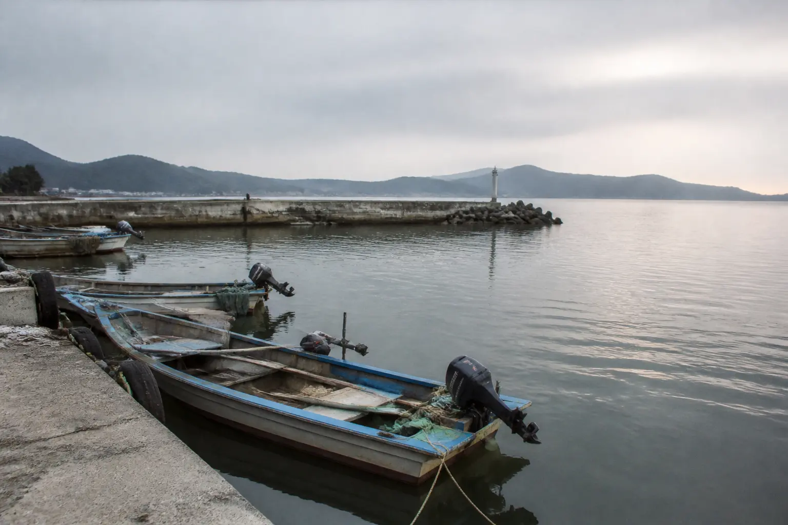 Small boats moored in a quiet harbour on the Korean peninsula's east coast under an overcast sky