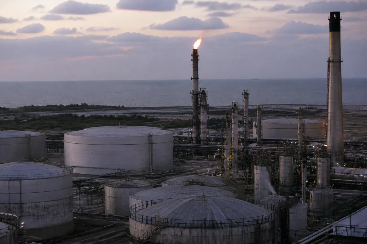 Storage tanks and towers of a coastal oil refinery at dusk