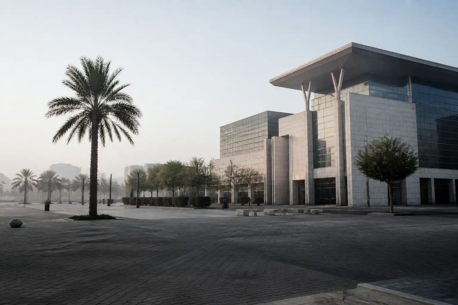 A modern conference centre plaza in a Gulf city at dawn, empty of people.