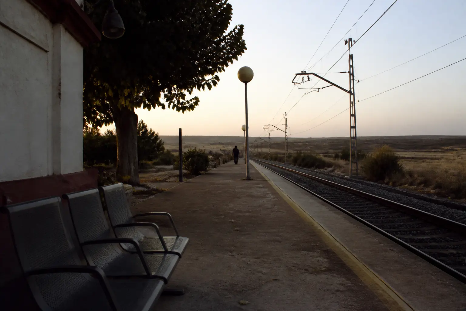 An empty railway platform in a small town on Spain's central plain at dawn.