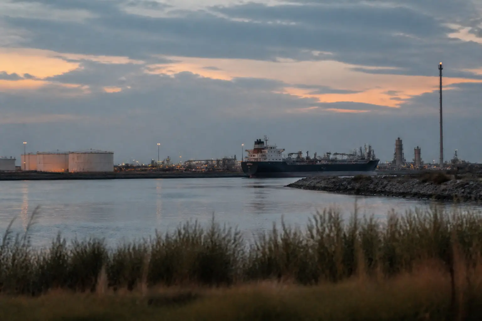 Öltanks und ein Tanker in einem ruhigen Hafen an der texanischen Golfküste in der Abenddämmerung